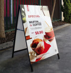 Black A-frame outside a cafe with a printed muffin and coffee special poster