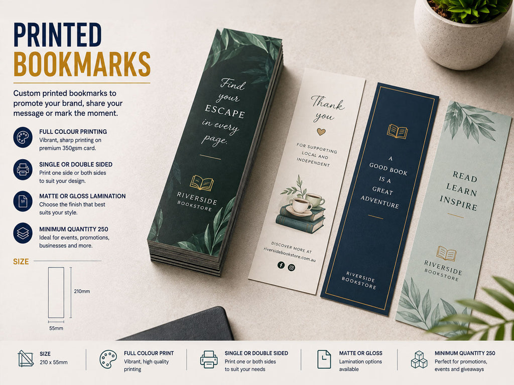 Printed bookmarks in green, navy and cream fanned across a desk beside a stack of matching bookmarks