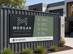 Colorbond steel sign for a construction company mounted on a dark fence outside a modern office