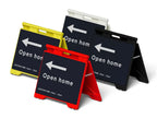 Four plastic Evarite A-frame signs in yellow, white, red and black, each holding an Open Home directional insert