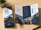 Tri-fold construction company brochure lying open on a wooden desk beside a folded copy