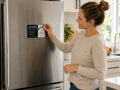 Woman placing a printed fridge magnet for a plumbing company on a stainless steel fridge door