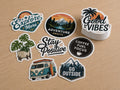 Individually cut vinyl stickers with outdoor and travel designs laid out on a light timber desk