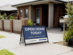 Black A-frame sign on a suburban footpath outside a brick house, reading Open Home Today with inspection times