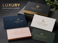 Luxury business cards with gold foil, embossing and coloured edges arranged on a dark stone surface