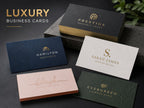 Luxury business cards with gold foil, embossing and coloured edges arranged on a dark stone surface
