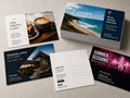 Printed postcards for a cafe, a travel brand, a property listing and a music festival, with a blank reverse showing the address panel