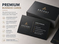 Premium black business cards with gold foil detailing, stacked and fanned on a pale surface