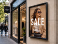 Framed sale poster mounted on the stone facade beside the entrance of a clothing boutique