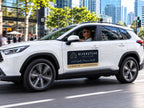 White SUV driving through a city street with a printed vehicle magnet on the door for a real estate agency